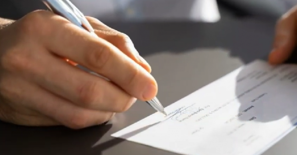 Hand with pen filling out a check