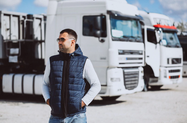 man standing with 2 parked trucks behind