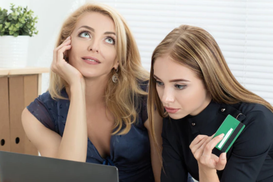 2 women doing online shopping with credit card in hands