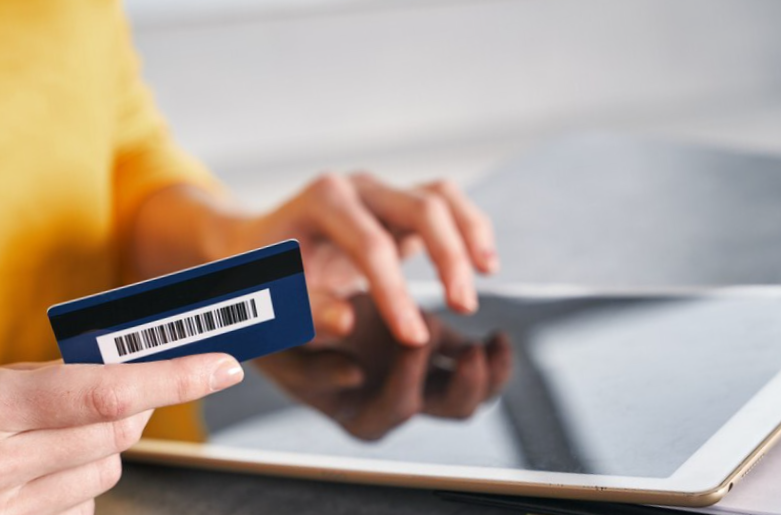 close up shot of bank card in hand of woman shopping online from home
