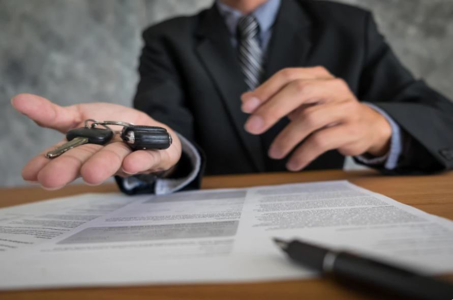 sales man holding cars key over documents