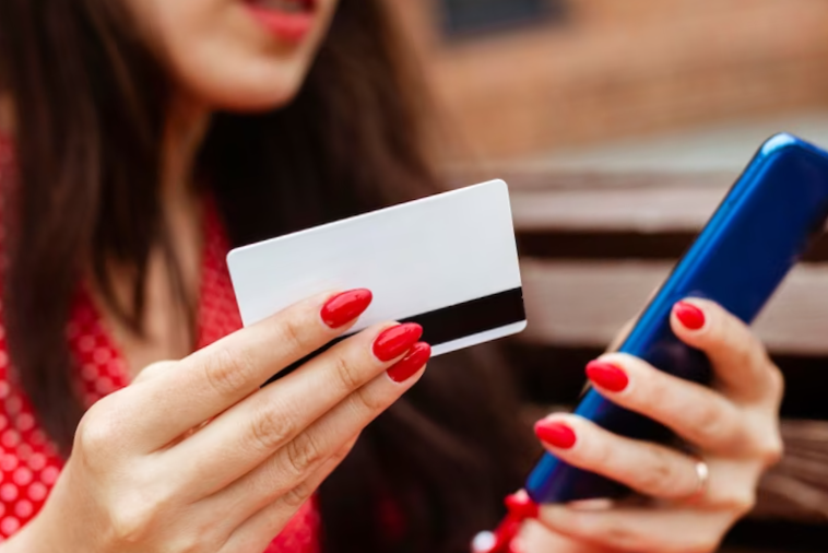 side view of woman with smartphone and credit card purchasing online
