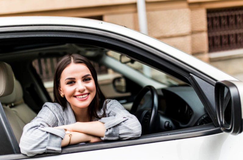 Closeup portrait smiling young woman sitting in her new car 